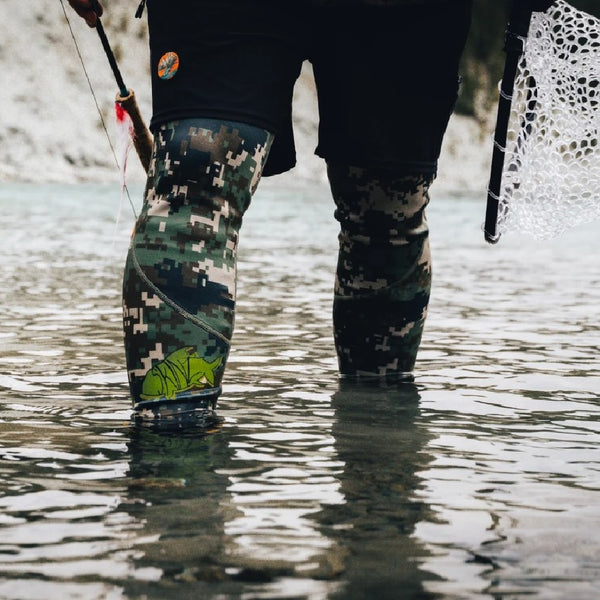 Man wearing the green camo Backcountry Skinz Airblitz Neoprene Wet Wading Pants while fishing in a body of water.