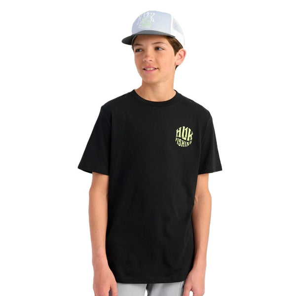 Person wearing a black Huk Outta This World t-shirt with graphics and text, standing against a white background