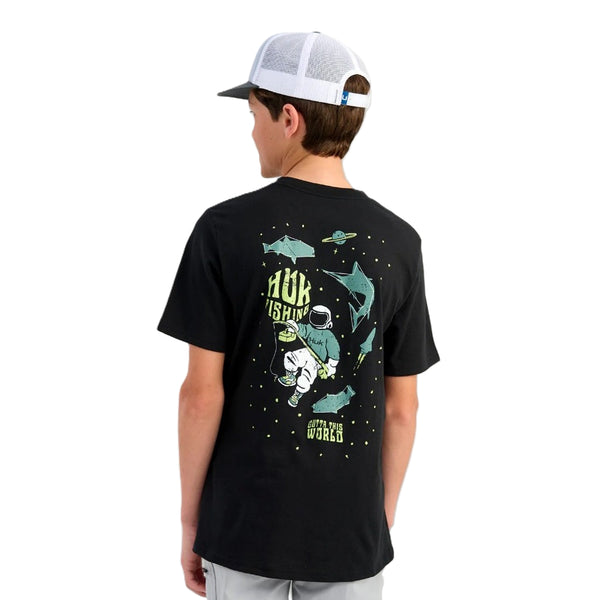 Person wearing a black Huk Outta This World t-shirt with graphics and text, standing against a white background