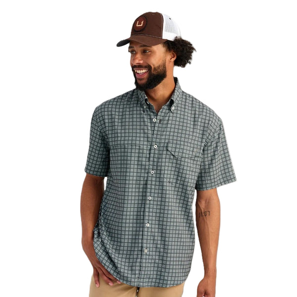 Man wearing a mini checkered print Huk Short-Sleeve Tide Point Shirt on a white background.