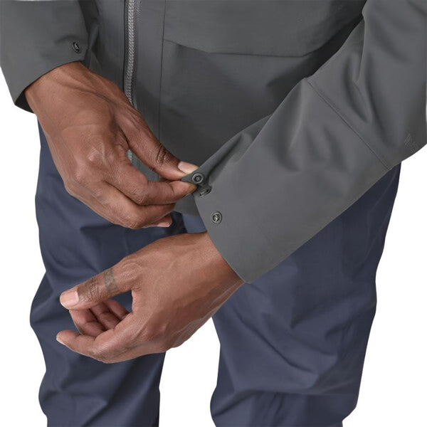 Person wearing a Patagonia Men's Swiftcurrent Wading Jacket in forge grey color showing cuff details on a white background.