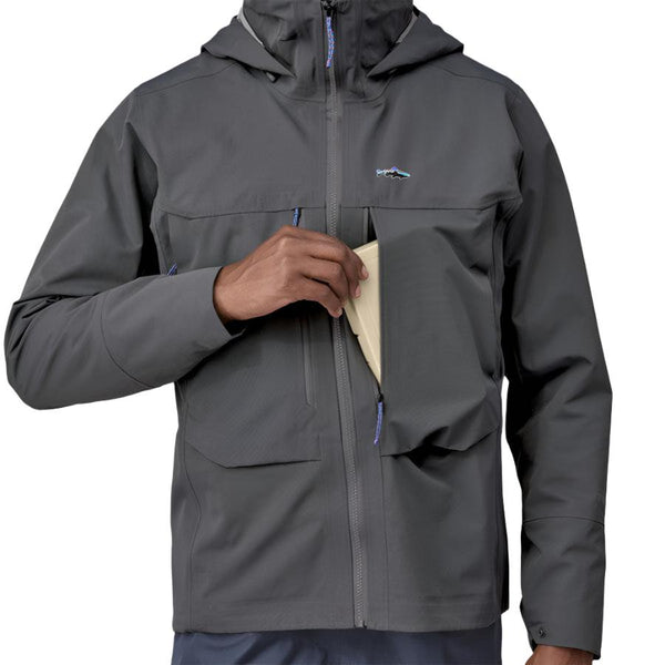 Person wearing a Patagonia Men's Swiftcurrent Wading Jacket in forge grey color showing pocket details on a white background.