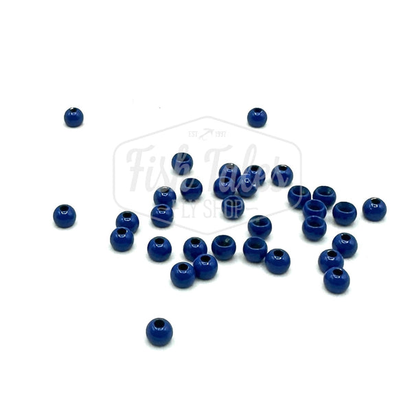 A collection of blue brass fly tying beads scattered on a white surface.