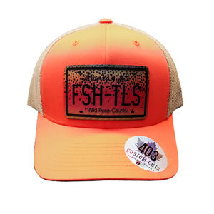 Orange and tan trucker cap with a black patch featuring cutthroat trout 'Fish Tales Fly Shop' Alberta license plate logo patch, on a white background.