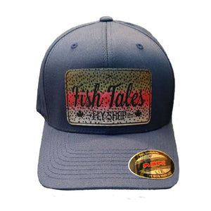 Navy blue Flex Fit hat with rainbow trout 'Fish Tales Fly Shop' logo patch, on a white background.