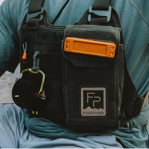 Person in blue clothing wearing Fishpond Stormshadow Chest Pack Waxed Cotton in duskwood color.