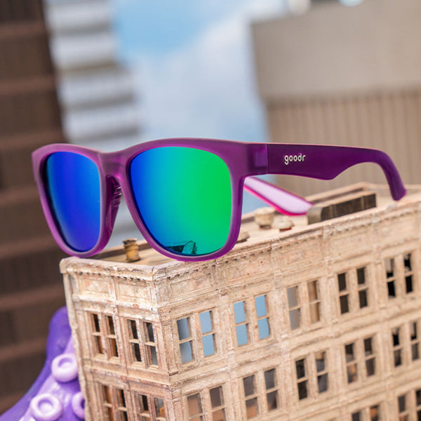 Purple Goodr BFG sunglasses with mirrored blue lenses on a small model building.