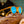 Orange Goodr Circle G sunglasses with blue lenses on a loaf of bread against a blurred background.