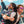 Two people wearing Goodr Strange Things are Afoot at the Circle G Sunglasses with white frame and pink lenses with clear sky and buildings in the background.