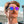 Person wearing Goodr Strange Things are Afoot at the Circle G Sunglasses with white frame and pink lenses with clear sky and buildings in the background.