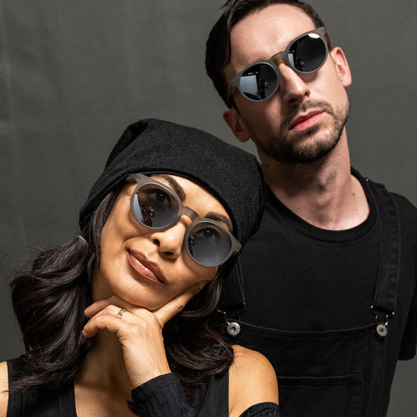 Two people wearing Goodr Circle G sunglasses against a dark background.