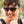 Man wearing Goodr Flex G Lawn Mower Drag Race Sunglasses with green frame and brown gradient lens on a blurred natural background.