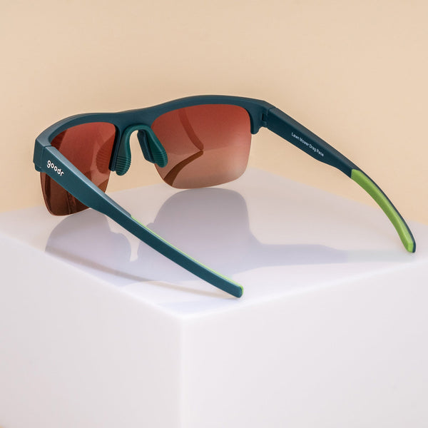 Goodr Flex G Lawn Mower Drag Race Sunglasses with green frame and brown gradient lens on a neutral background.