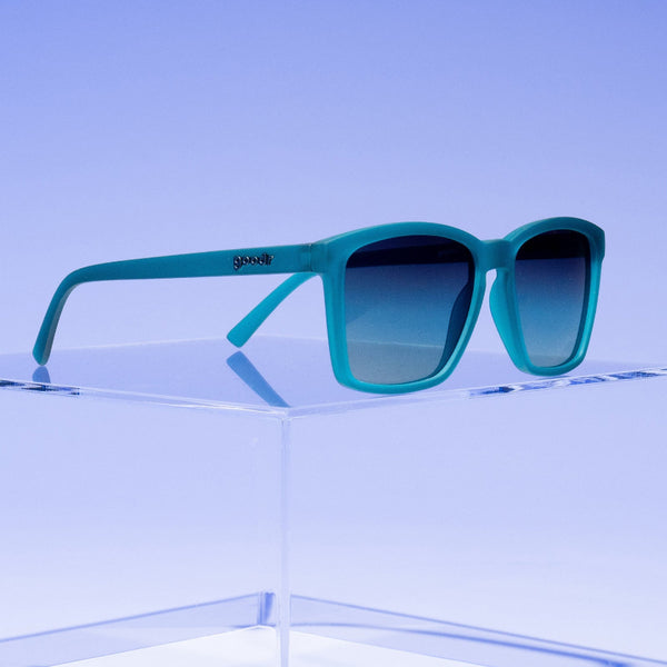 Goodr LFG Dungaree Debauchery blue sunglasses on a blue grey background.