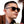 Person wearing Goodr LFG Sunglasses with tortoiseshell frame and brown lenses on a white background.