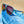 Goodr Mach G Frequent Skymall Shoppers Sunglasses with blue frame and yellow accents on a blue and tan background.