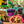 Toy skeleton and dinosaur figures in sand with the Goodr OG Electric Dinotopia Carnival sunglasses with a beachy background.