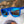 Blue Goodr OG Falkor's Fever Dream sunglasses on a furry white surface against a blurred natural background.