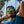 Man wearing Turquoise Goodr OG sunglasses with green lenses with palm trees in the background.