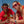 Two people in red wearing Goodr OG Phoenix at a Bloody Mary Bar Polarized Sunglasses and holding Bloody Mary drinks with a clear blue sky in the background.
