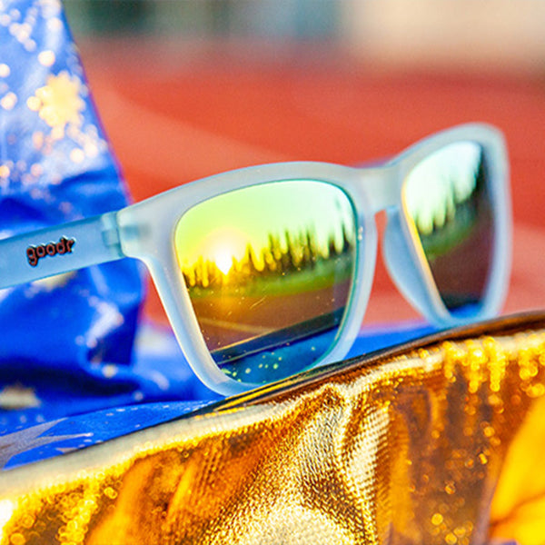 Goodr OG Sunbathing With Wizards Sunglasses with mirror lenses on a white background on a wizard hat against a blurred background.