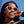 Woman wearing beige Goodr OG Toasted Marshmallow Magic sunglasses with brown gradient lenses with a clear blue sky background.