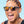 Person wearing Goodr OG Whiskey Shots With Satan Sunglasses and a colorful head wrap with a clear blue sky background.