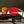 Goodr VRG Voight Kampff Vision Sunglasses with mirrored orange lenses and black frame sitting on electronics over a grey background.