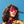 Person wearing Goodr VRG Voight Kampff Vision Sunglasses with mirrored red/orange lenses and black frame on a sky blue background.