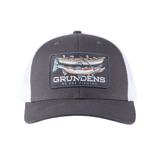 A gray and white trucker hat  from Grundéns with a logo and an illustration of a drift boat and a giant trout on the front, over a white background. 