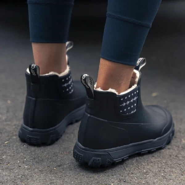 Person wearing the Grundens Women's Deviation Sherpa Ankle Boot in black on pavement.