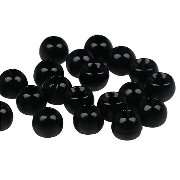 A large group of glossy jet black cyclops tungsten beads for fly tying on a white background.