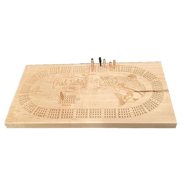 Angled view of a 4-track wooden cribbage board made with maple with engraved fly fishing design, on a white background.