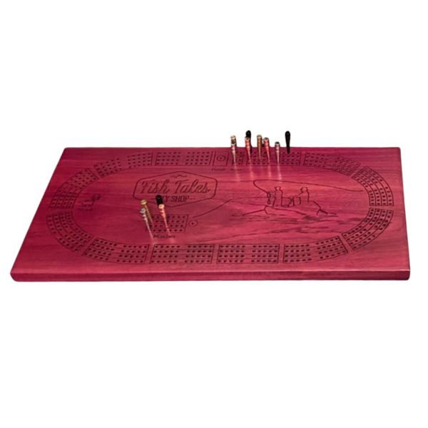 Angled view of a 4-track wooden cribbage board made with purple heart wood with engraved fly fishing design, on a white background.