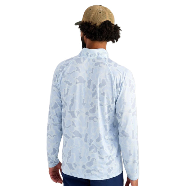 Man wearing a light blue Huk KC Camouflage Men's Airweight 1/4 Zip long-sleeve shirt on a white background.