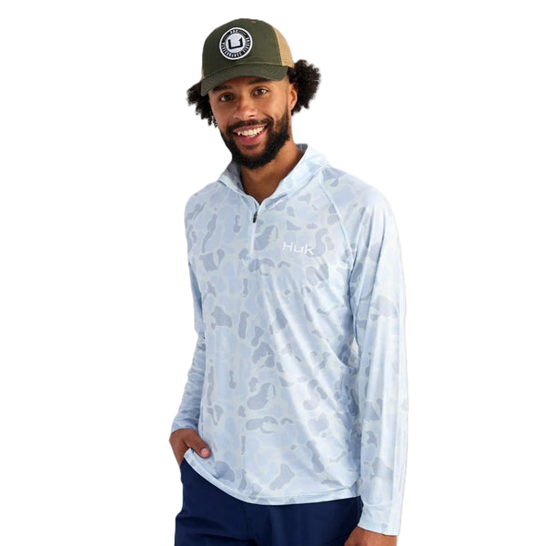 Man wearing a light blue Huk KC Camouflage Men's Airweight 1/4 Zip long-sleeve shirt on a white background