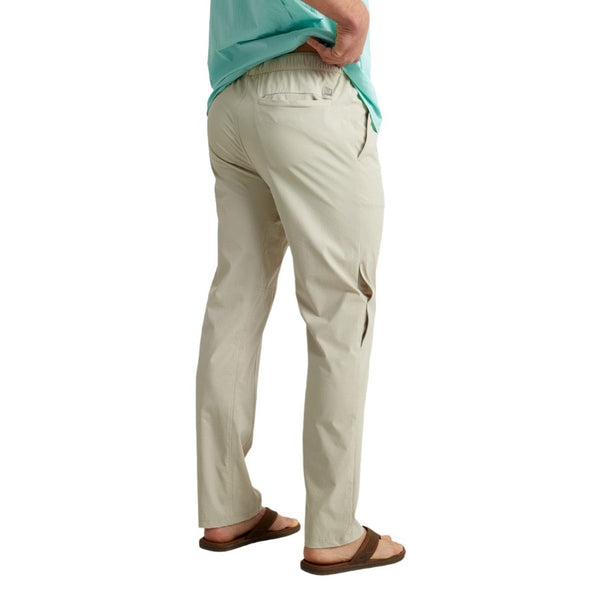 back view of a man wearing khaki huk fishing men's creekbed wet wading pants on a white background
