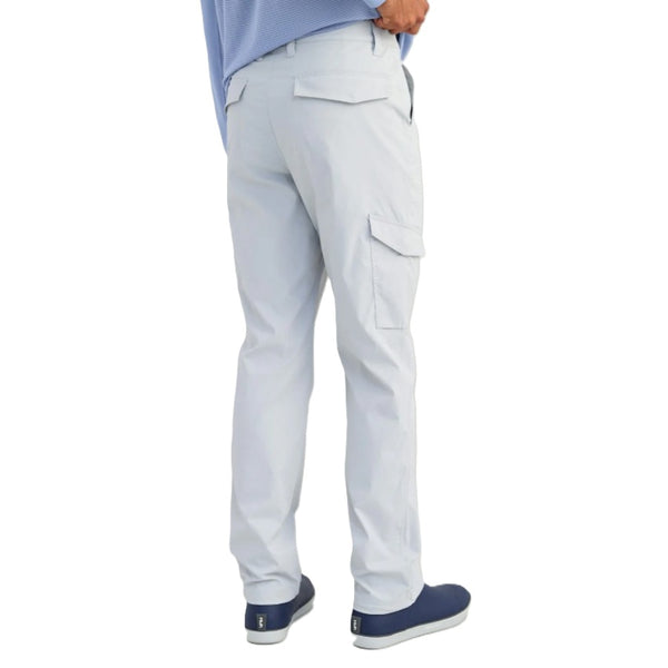 Person wearing harbor mist grey Huk Men's Icon Performance Pants and navy shoes on a white background.