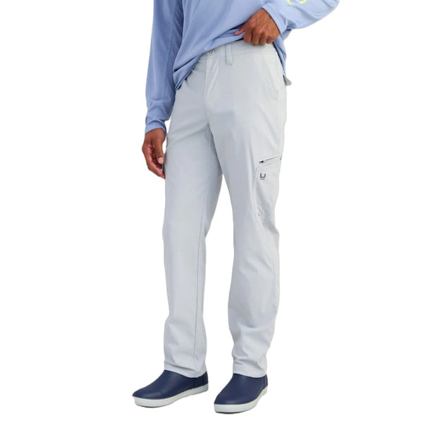 Person wearing harbor mist grey Huk Men's Icon Performance Pants and navy shoes on a white background.