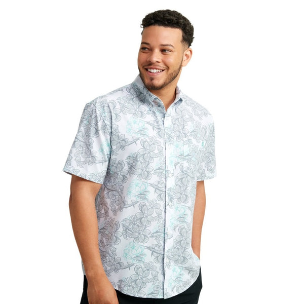 front view of a man wearing a kc desert rose print white and grey huk fishing men's kona button down short sleeve shirt on a white background