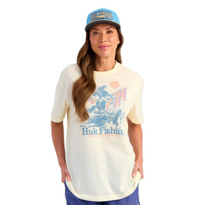 Woman wearing a Huk Fishing Trout Wranger t-shirt and cap on a white background.