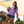 a smiling woman holding a coconut drink wearing a lilac purple huk fishing womens waypoint performance long sleeved sun hoody and blue shorts with palm trees in background