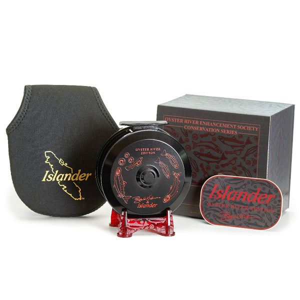 The Islander TR3 Trolling Reel - Oyster River Edition in black with red engraved artwork along with box and black neoprene reel pouch, on a white background.