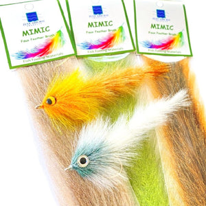 Several packaged Just Add H2O Mimic Faux Feather Brushes with 2 sample gamechanger streamers for fly fishing tied with this material, against a white background.
