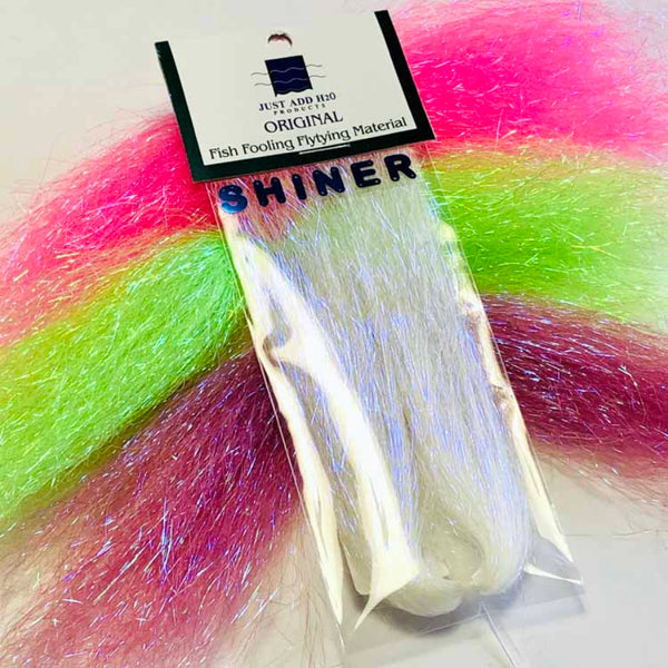 Packaged Just Add H2O Shiner Flash for fly tying over skeins of Shiner Flash in various colors on a white background.
