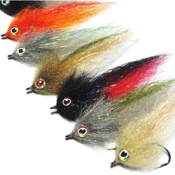 Group of several baitfish streamers tied with Just Add H2O Streamer Brushes in a variety of colors, arranged diagonally on a white background.