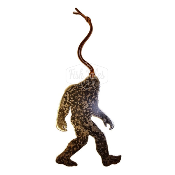 A Sasquatch MK Steel fly fishing ornament in dark steel with a leather hanger, in the shape of a walking bigfoot in profile.