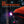 Person wearing an orange beanie with a neebo illumatrace blood tracker headlamp in rain, IPX6 water-resistant text above.