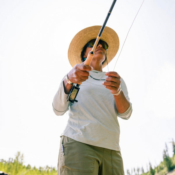 Person holding an Orvis Helios 50th Anniversary fly fishing rod with a blurred natural background.