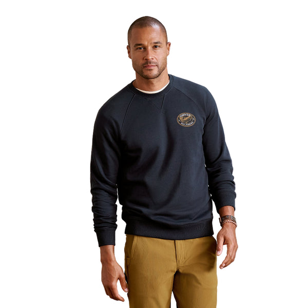 Man wearing khaki pants and the navy blue Orvis Men's Campfire Crewneck Pullover Sweatshirt with a logo on the chest, against a white background.